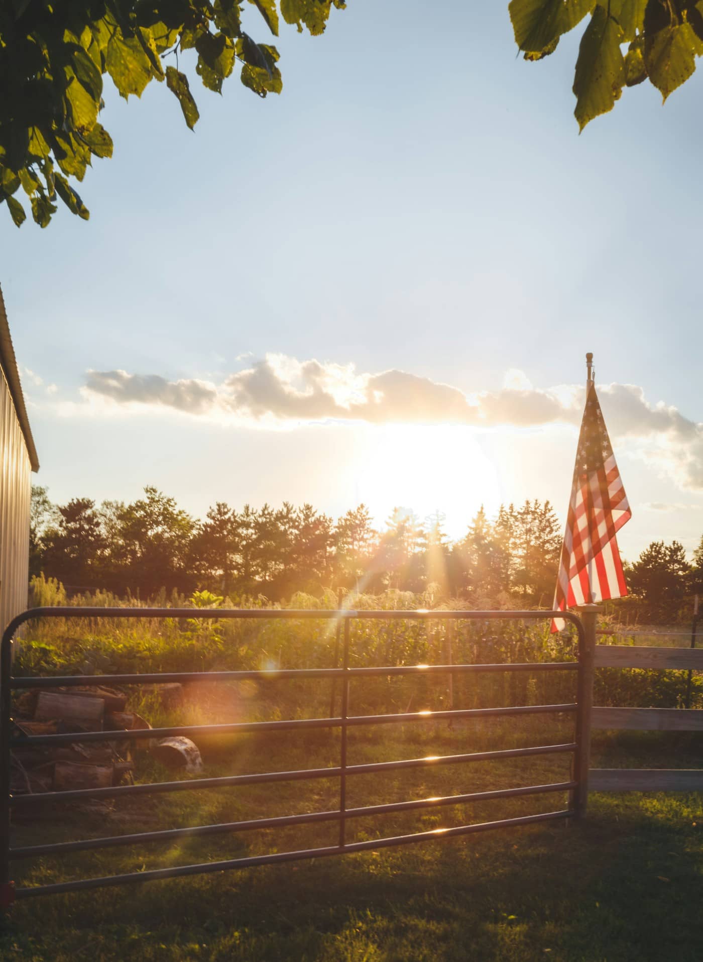 Portón de una granja al atardecer, con la bandera de Estados Unidos al lado